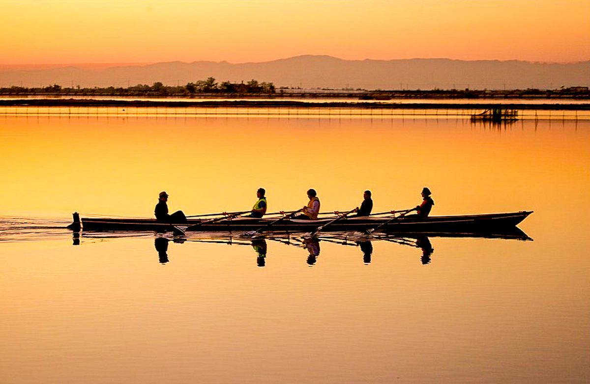 Silhouette di un'imbarcazione da voga con vogatori in laguna al tramonto – foto di ©mircobassoph